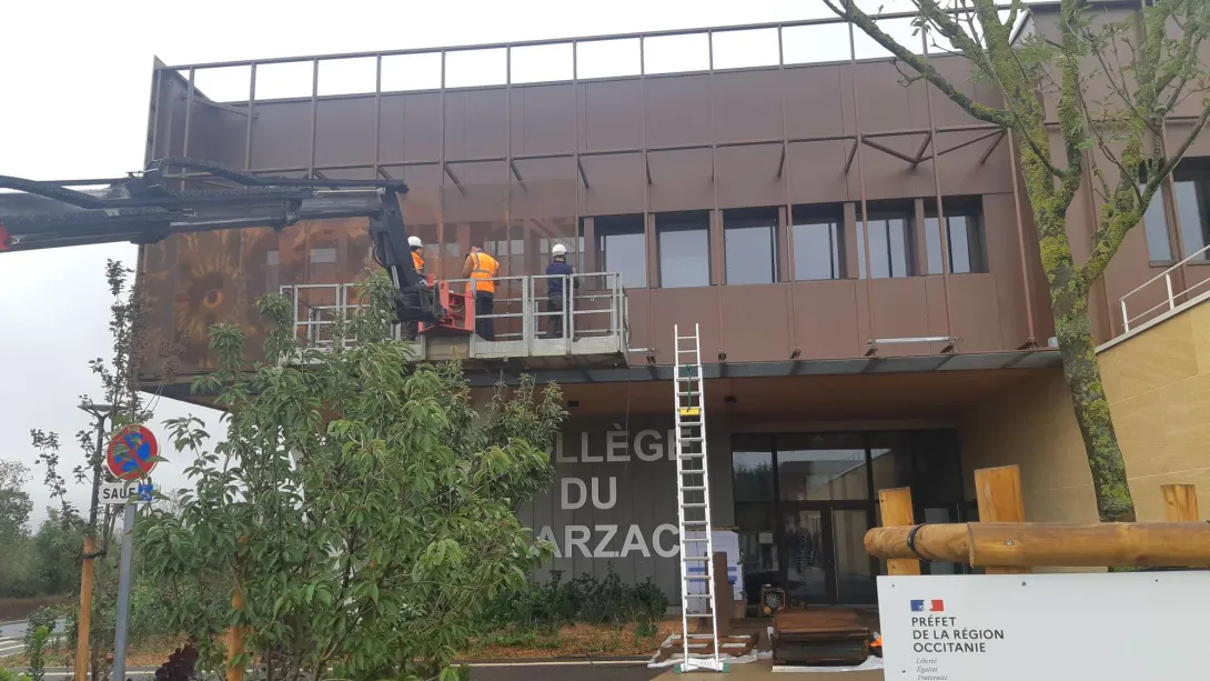 L'entreprise Maliges à l'oeuvre pour réaliser le motif de la Cardabelle, chardon emblématique des causses, sur la résine microperforée en acier corten de la façade du collège