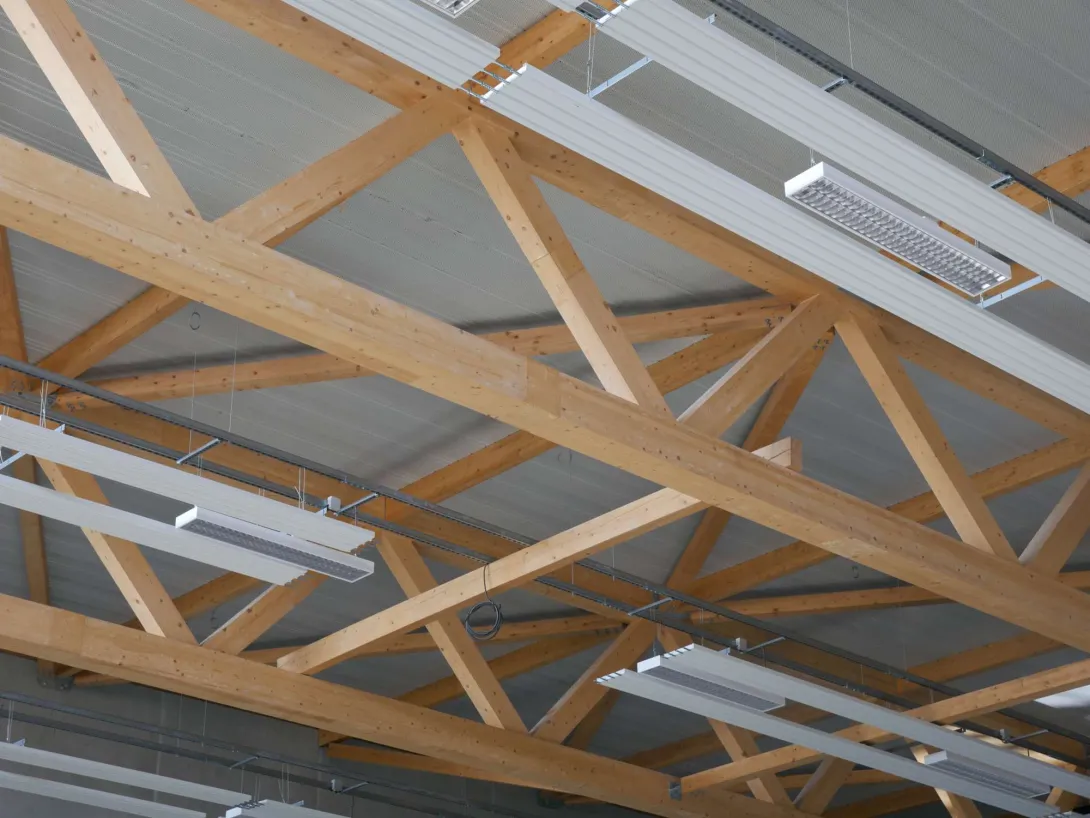 Vue sur le plafond du gymnase : charpente bois, bacs acier acoustiques, panneaux rayonnants et luminaires sportifs